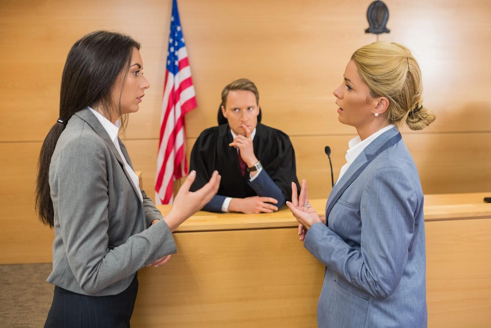 Two attorneys address each other during a sidebar as the judge looks on; business litigation discussion. 