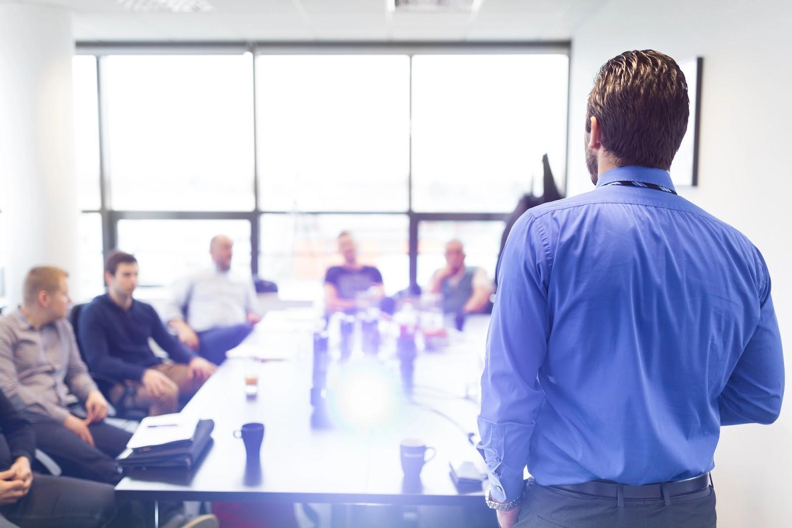 A man addressing a room full of businessmen.