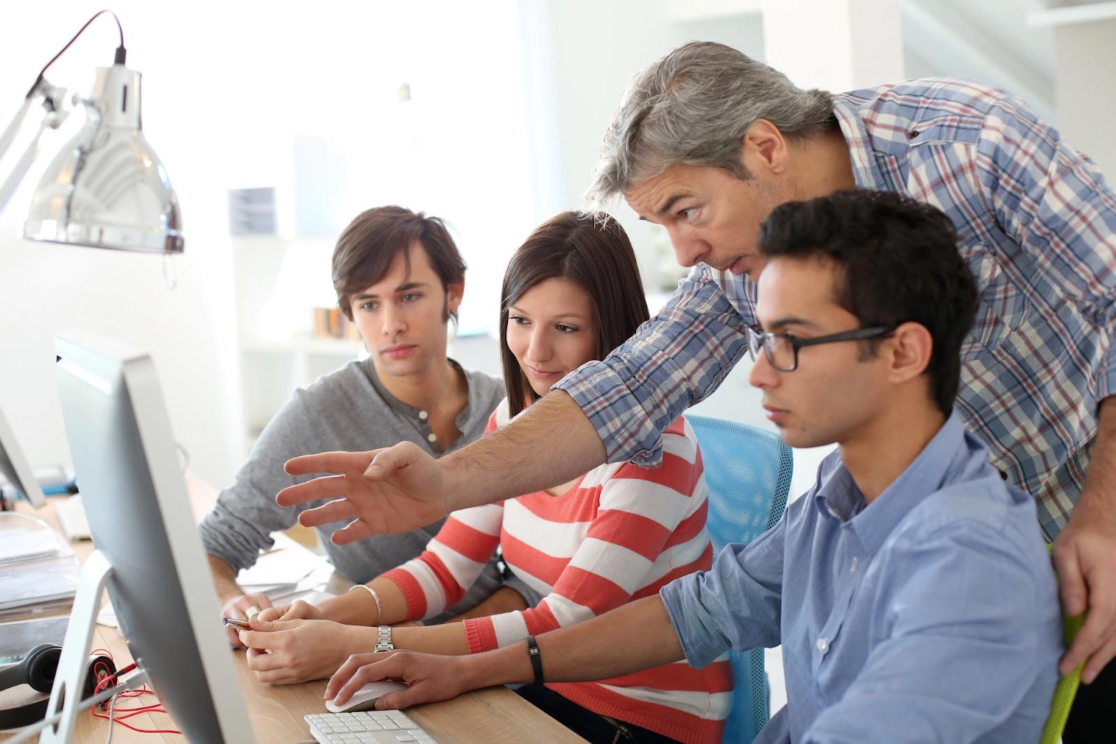 Supervisor instructing unpaid interns on computer program