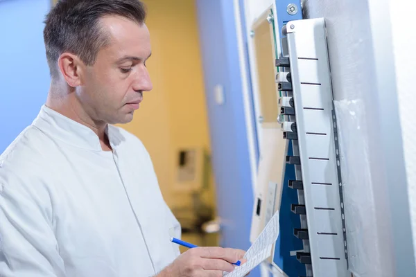 Manager next to the time-stamping machine for employees, reviewing time cards